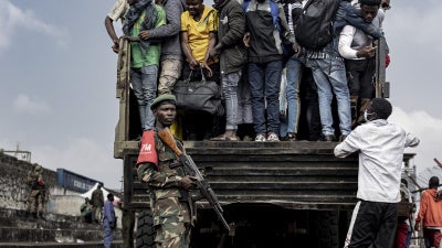 M23 fighters stand guard as people board a truck