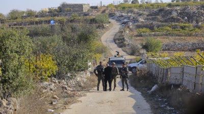 Palästinenser stehen hinter einer Absperrung, während israelische Streitkräfte am 20. November 2025 in der Ortschaft Halhul in der Nähe von Hebron im besetzten Westjordanland Bauern den Zugang zu ihren Feldern verwehren.
