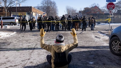 Ein Demonstrant sitzt mit erhobenen Händen vor Bundesbeamten und der Polizei von Minneapolis auf der Straße an der Ecke W. 27th St und Nicollet Avenue im Süden von Minneapolis, nachdem Alex Pretti dort am Morgen des Samstags, dem 24. Januar 2026, von Bundesbeamten tödlich erschossen worden war.
