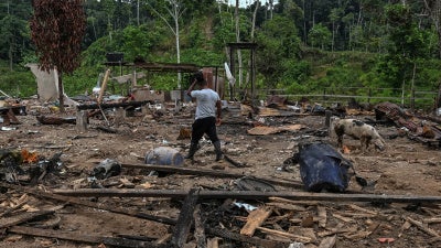 A farmer walks amidst rubble