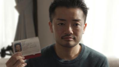 トランスジェンダー男性の杉山文野さん。性別が女性と記されたパスポートのページを掲げる。都内の自宅にて撮影。