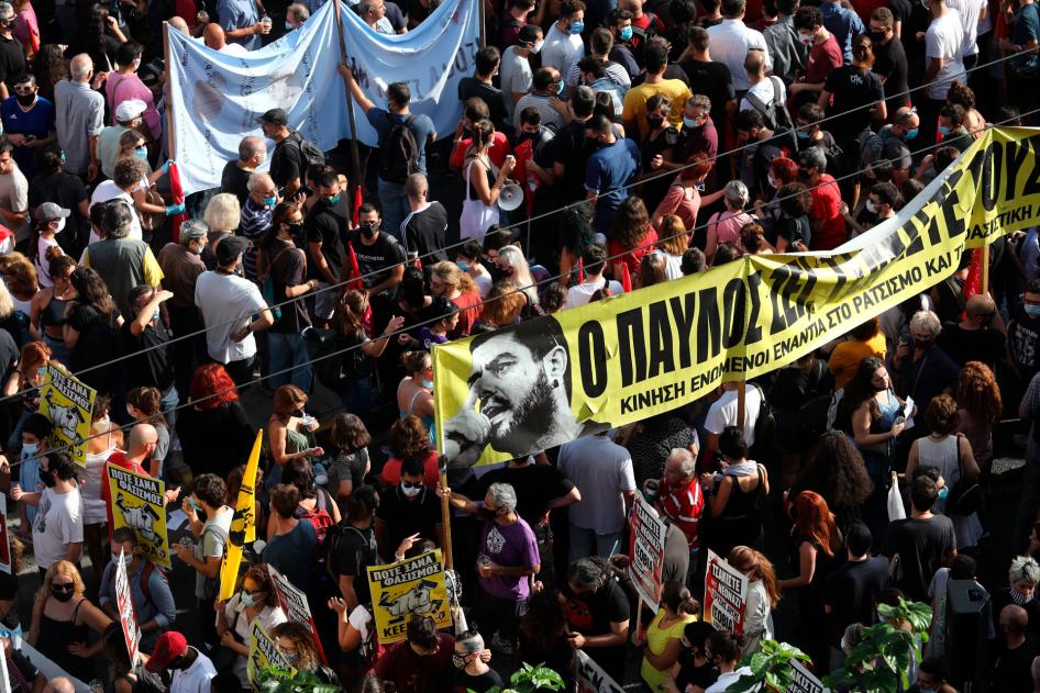 People holding a banner depicting Greek rap singer Pavlos Fyssas, who was stabbed and killed by a supporter of the extreme right Golden Dawn party in 2013, gather for a protest outside a court in Athens, Wednesday, October 7, 2020. 