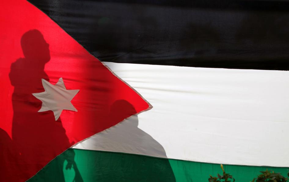 Silhouettes are cast on a Jordanian national flag in Amman, Jordan, November 30, 2016. 