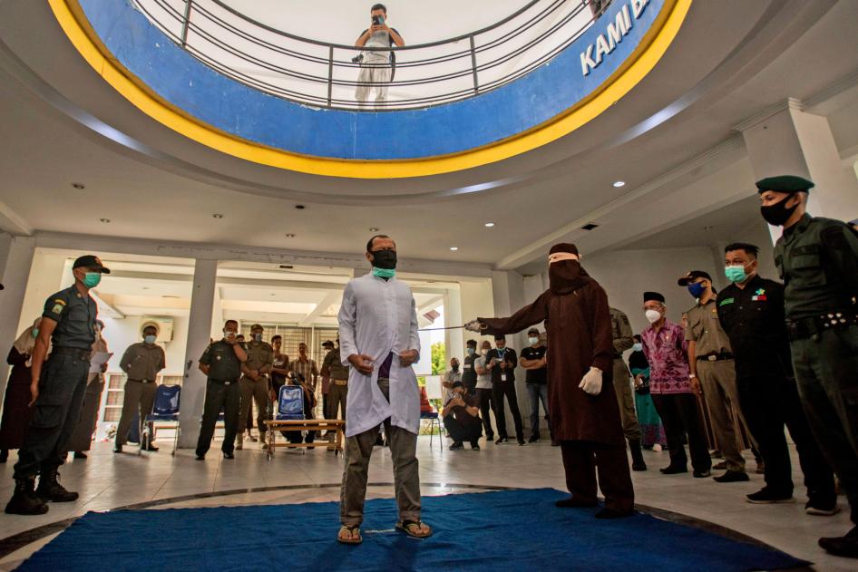 A Shariah law official uses a rattan cane to whip one of two men convicted of gay sex in Banda Aceh, Aceh province, Indonesia, January 28, 2021. 