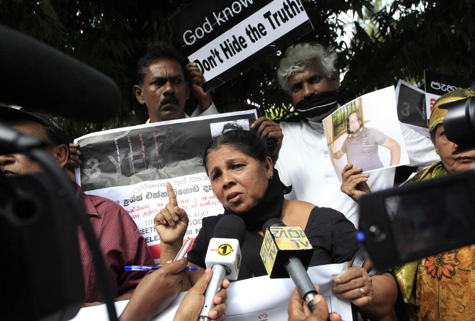 A woman speaking to reporters holding microphones