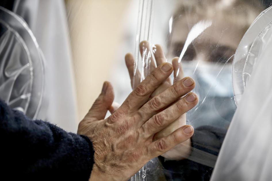 Des proches se touchent la main à travers un rideau en plastique  afin d'éviter de contracter le Covid-19 au centre médical San Raffaele à Rome (Italie), le 22 décembre 2020.