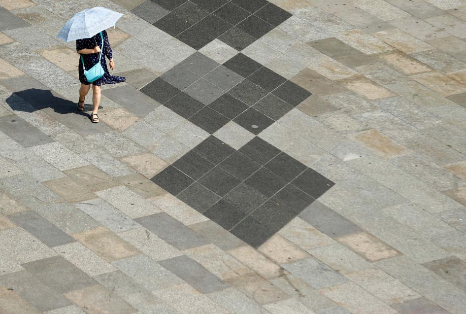 A woman shields herself from the sun with an umbrella on a hot summer day in Cologne, Germany, July 25, 2019. 