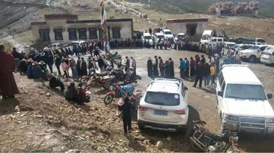 A large crowd standing in a circle outside of a monastery building