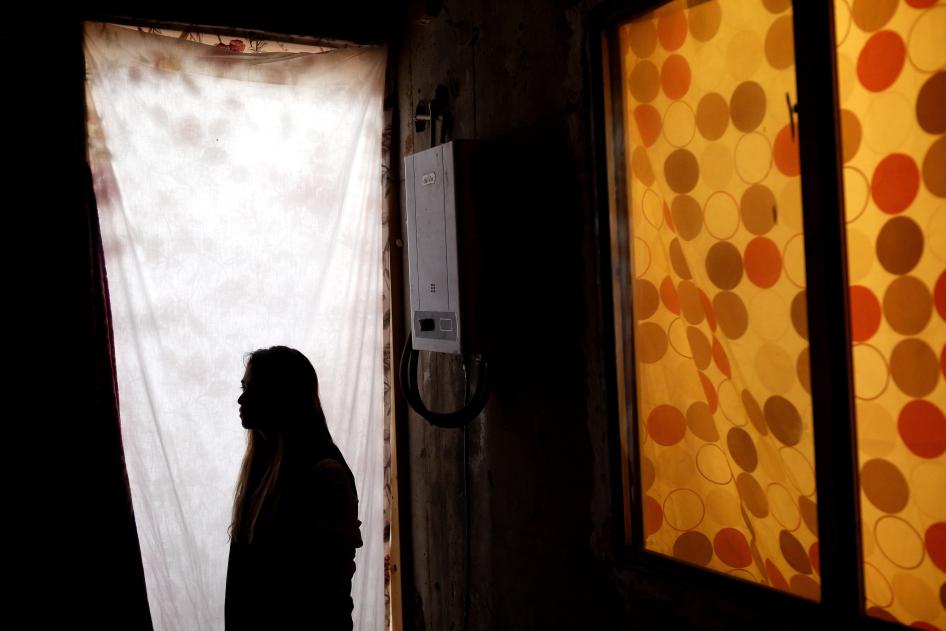 Woman stands in profile with in a doorframe, her face is obscured