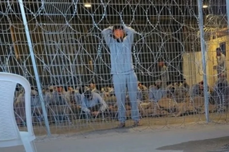 Une photo du centre de détention de la base militaire de Sde Teiman dans le désert du Negev en Israël, prise clandestinement, montre un détenu debout, les yeux bandés et les mains derrière la tête.