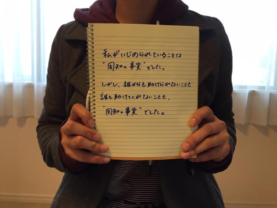 A 20 year old Japanese woman who was bullied by her classmates in junior high school holds a notebook displaying the message...