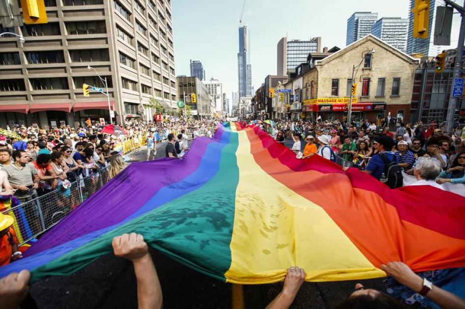 Revellers hold a giant pride flag during the "WorldPride" gay pride Parade in Toronto, June 29, 2014.