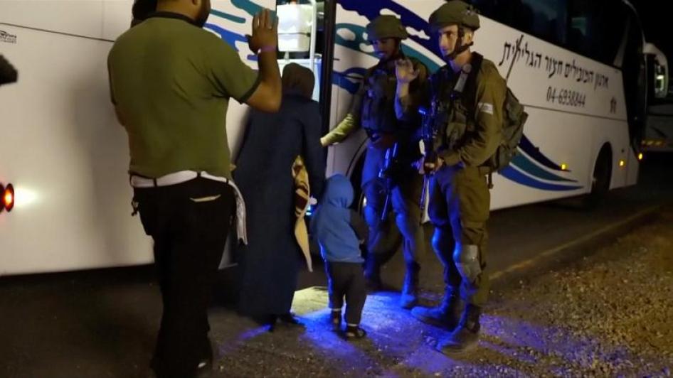 أشخاص يمرون بجانب جنود إسرائيليين وهم يصعدون باصا أثناء إخلاء "الدفاع المدني السوري"، المعروف أيضا بـ "الخوذ البيضاء"، من مرتفعات الجولان. هذه الصورة مأخوذة من فيديو نشره الجيش الإسرائيلي في 22 يوليو/تموز 2018.