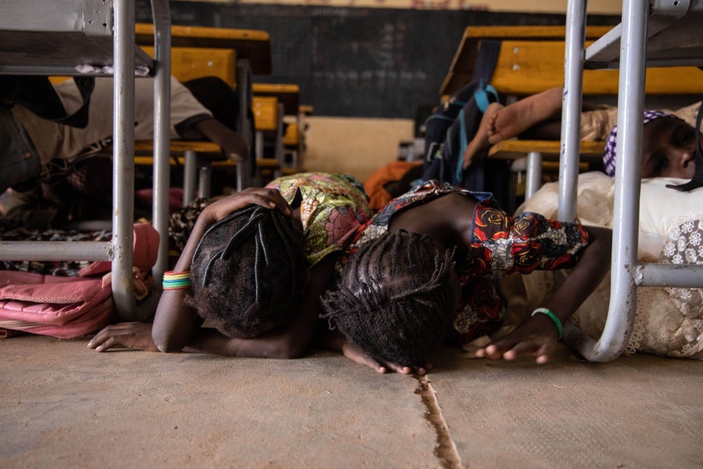 Young girls hide under a desk
