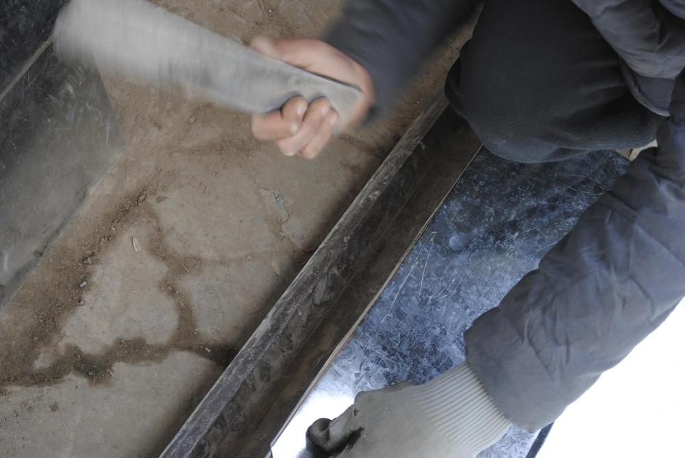 A young boy working at a metal workshop in Kabul hammers a metal sheet into a desired bend.    © 2016 Bethany Matta/Human Rights Watch.
