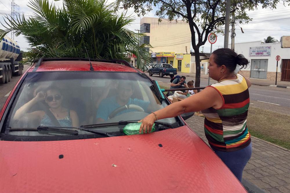 Uma imigrante venezuelana sem carteira de trabalho lava para-brisas em um semáforo em Boa Vista, capital de Roraima, em 11 de fevereiro de 2017. 