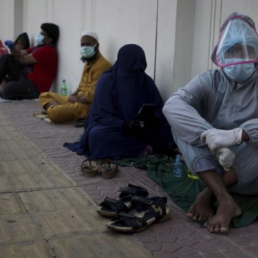 People in face masks seated on the floor in a line 