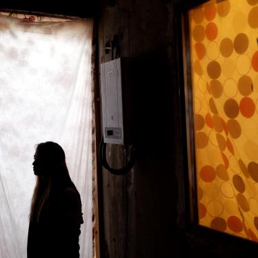 Woman stands in profile with in a doorframe, her face is obscured
