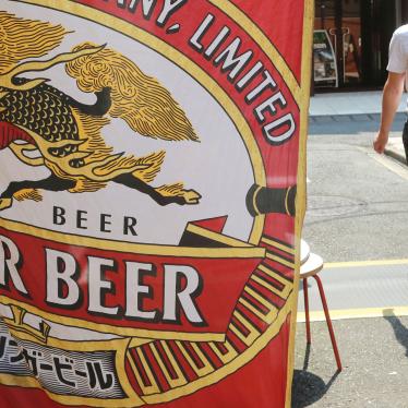 A man walks near an advertisement for a Kirin brand beer in Tokyo, Japan