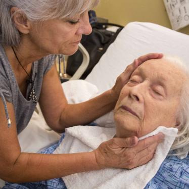 A woman tends to an older women lying in a bed