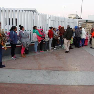Immigrants from Central America and Mexican citizens, who are fleeing from violence and poverty, queue to cross into the U.S. to apply for asylum.
